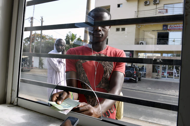 Un homme en chemise rouge tenant des billets de banque.