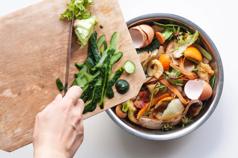 main qui jette des déchets au compost