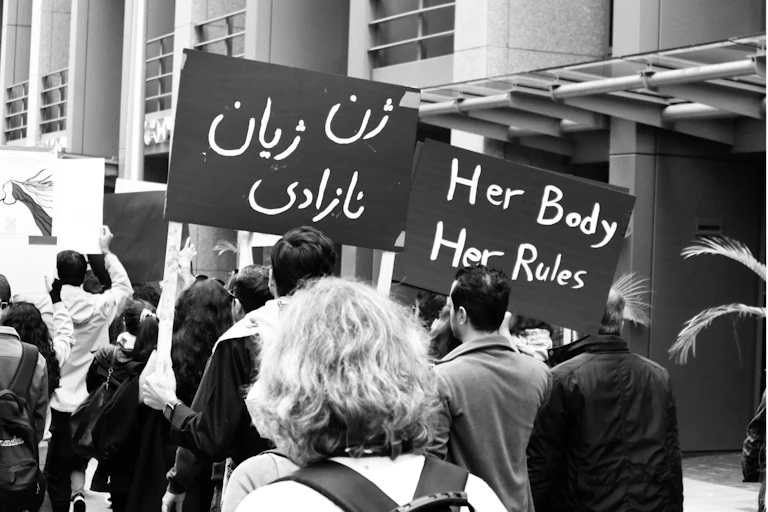 Men and women carrying banners in Farsi and English in support of women's rights in Iran.
