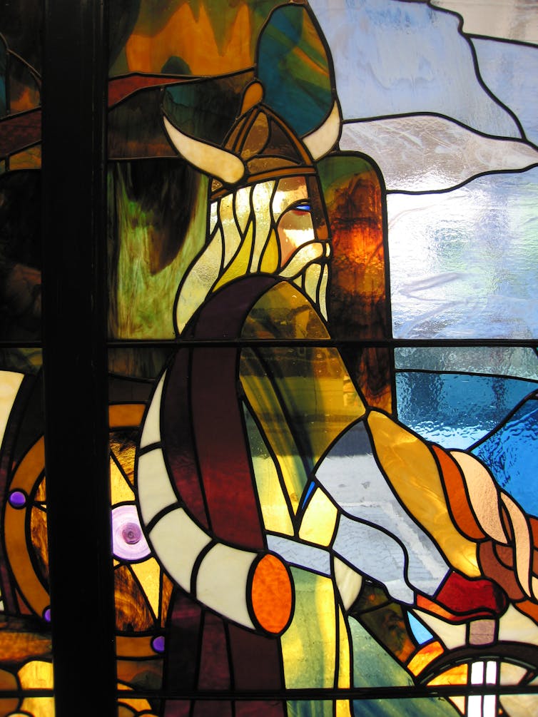 A stained-glass window showing a viking warrior looks at the sea.