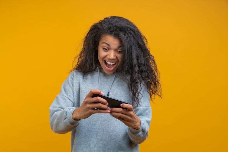 A girl looks excitedly at her cell phone.