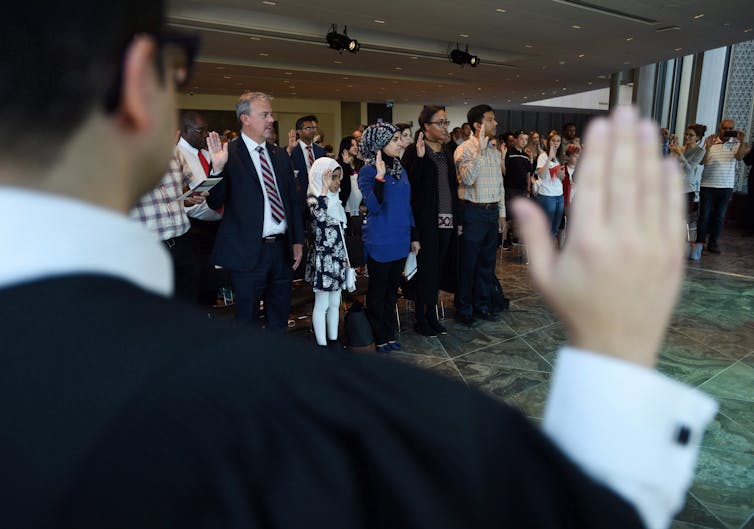 A group of people raise their right hands and they take an oath.