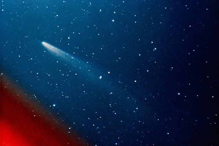 A blue star field with a red lower left corner and a bright streak angled towards top left