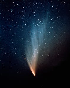 A dark star field with a blue glow in the middle and a bright orange streak illuminating the centre