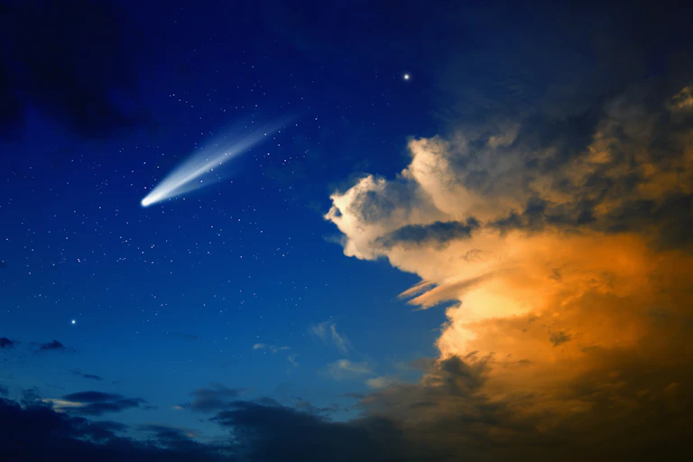 A blue sky with sunset clouds and a bright glow streaking towards the lower left