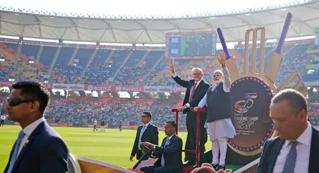 Indian Prime Minister Narendra Modi with his Australian counterpart Anthony Albanese waving at a cricket stadium