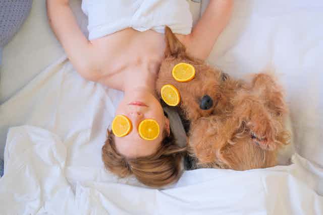 Una mujer y un perro con rodajas de naranja den los ojos en un día de spa.
