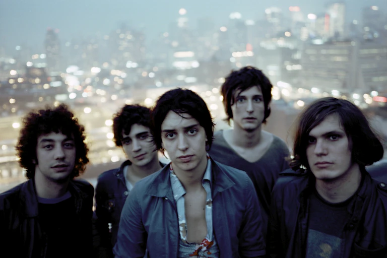 Five members of the Strokes stand in front of the New York skyline.