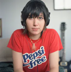 Karen O wears headphones and a red 'Pepsi free' T-shirt.