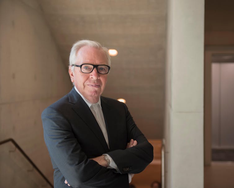 A grey-haired man with his arms crossed.