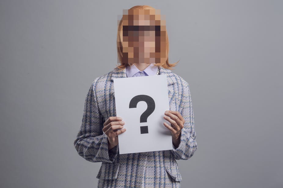 Woman holds placard with a question mark, her face is pixelated