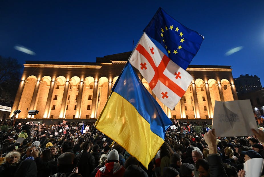 Drapeaux ukrainien, géorgien et européen brandis simultanément dans une manifestation devant le Parlement à Tbilissi, la nuit