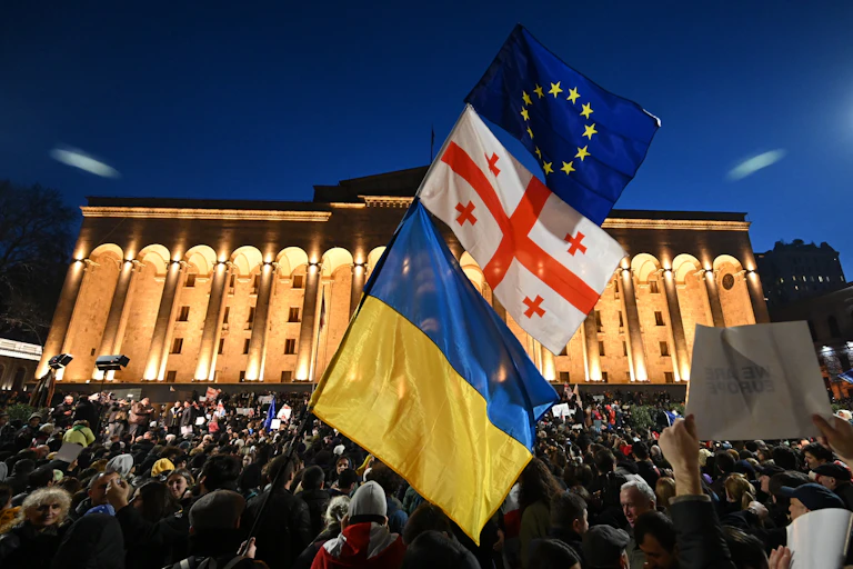 Drapeaux ukrainien, géorgien et européen brandis simultanément dans une manifestation devant le Parlement à Tbilissi, la nuit
