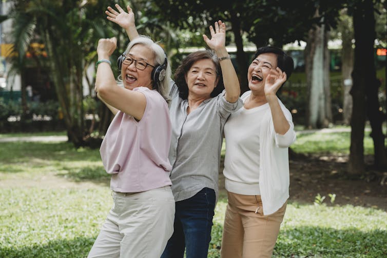 Three women dancing together in a park