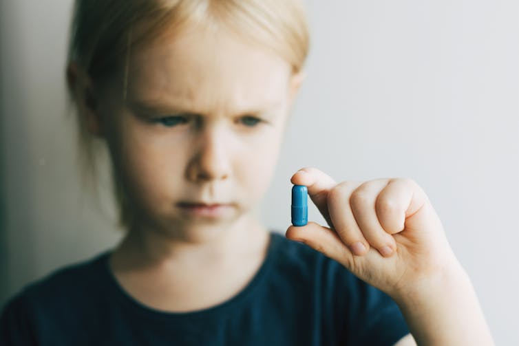 Une enfant songeuse tient une pilule
