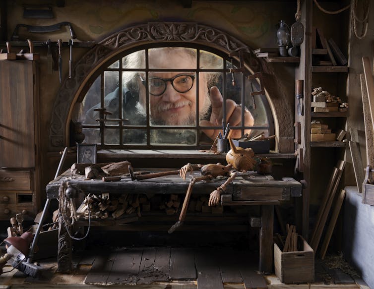 Guillermo del Toro looks through a window in the Pinocchio set.