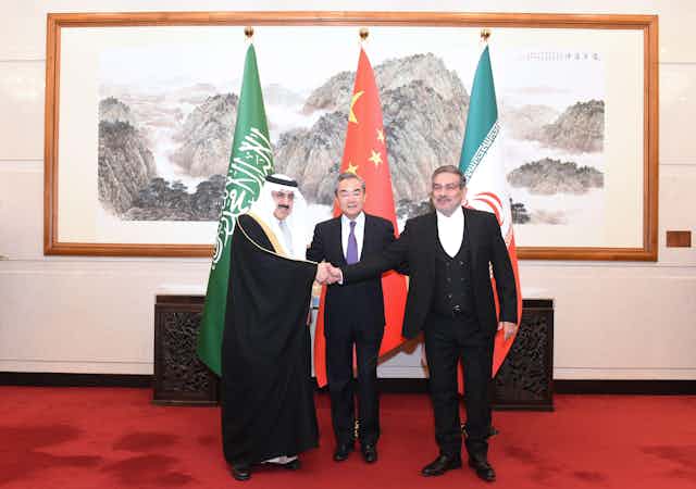 The Chinese foreign minister Wang Yi with deiplomats from Saudi Arabia and Iran shaking hands.