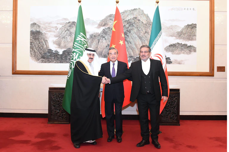 The Chinese foreign minister Wang Yi with deiplomats from Saudi Arabia and Iran shaking hands.