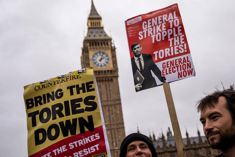 Protesters holding up placards outside parliament calling for a general strike