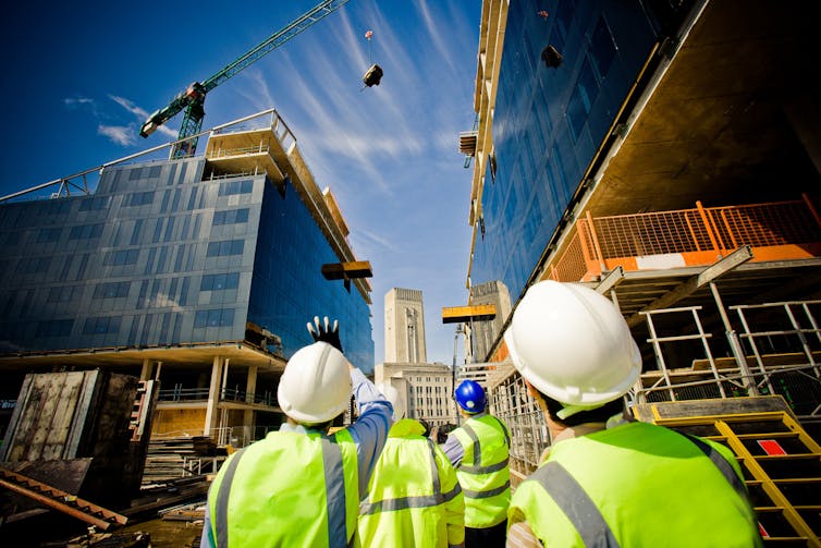 Builders looking up at a crane on a construction site