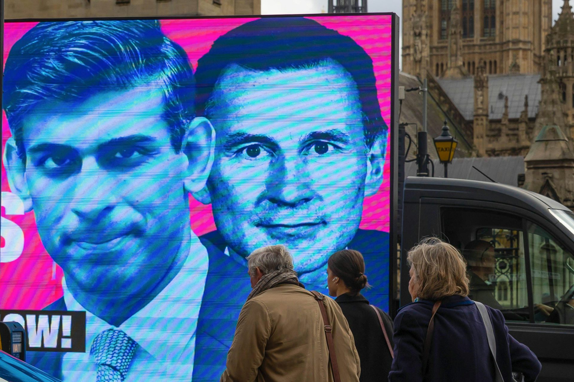 An image of Rishi Sunak and Jeremy Hunt being driven on the back of a van through London.