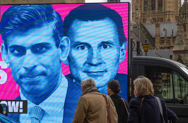 An image of Rishi Sunak and Jeremy Hunt being driven on the back of a van through London.