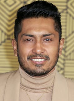 A man smiling against a patterned background.