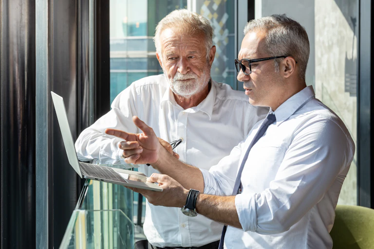 Deux hommes âgés discutent devant un ordinateur