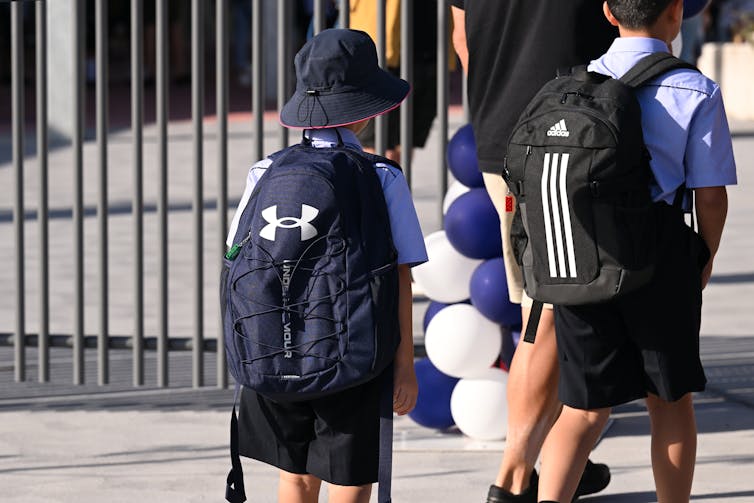 Two kids walk into a school together.