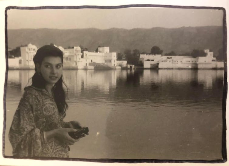 Young woman looking at camera, river and buildings behind her