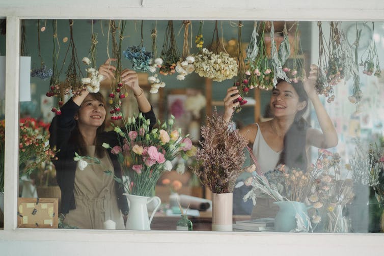 Woman hanging flowers in shop