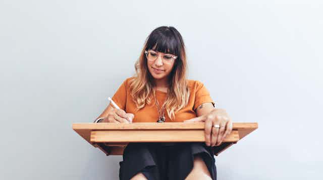 Woman sketching on wooden board.