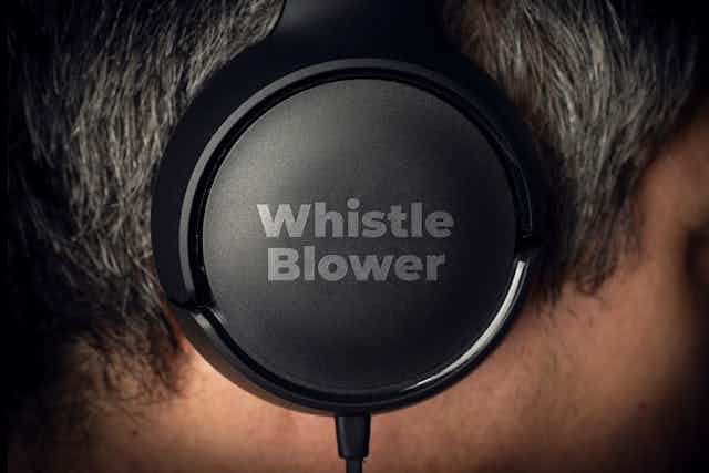 One side of a headphone in focus, with 'Whistle Blower' written on it.