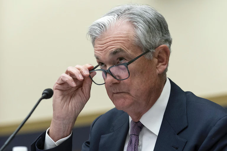 A man with gray hair fiddles with his glasses.