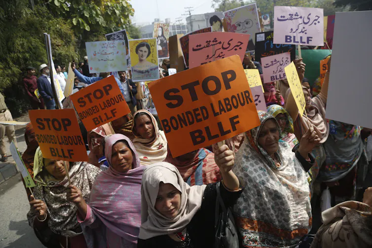 Pakistani women marching in the street holding signs that say 'Stop Bonded Labour BLLF'