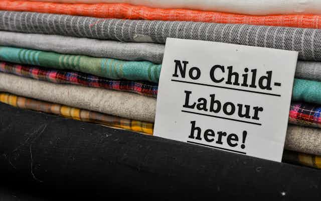 A note in front of a pile of folded fabric that says 'No Child Labour Here!'