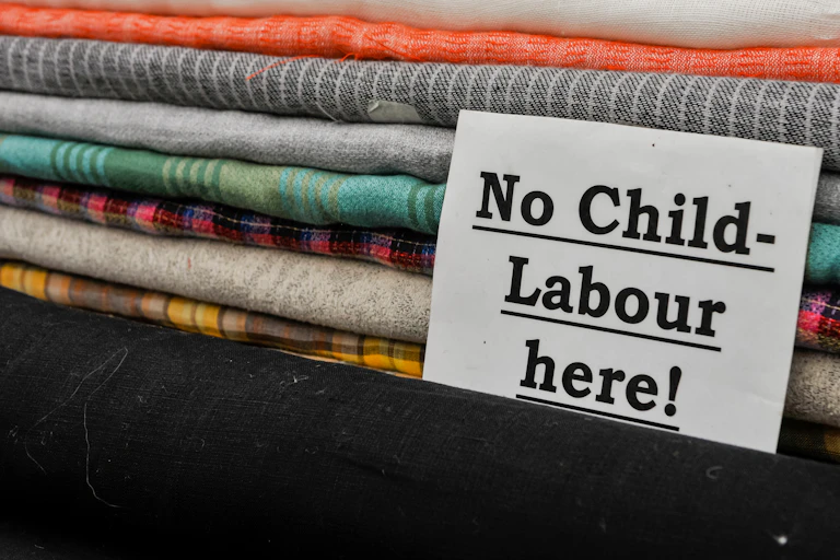 A note in front of a pile of folded fabric that says 'No Child Labour Here!'
