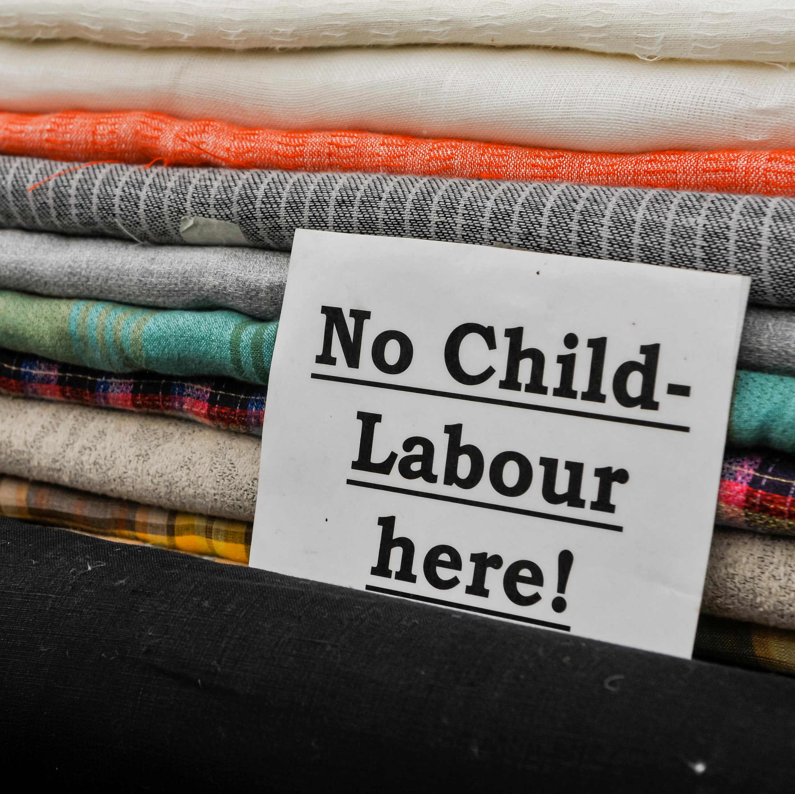 A note in front of a pile of folded fabric that says 'No Child Labour Here!'
