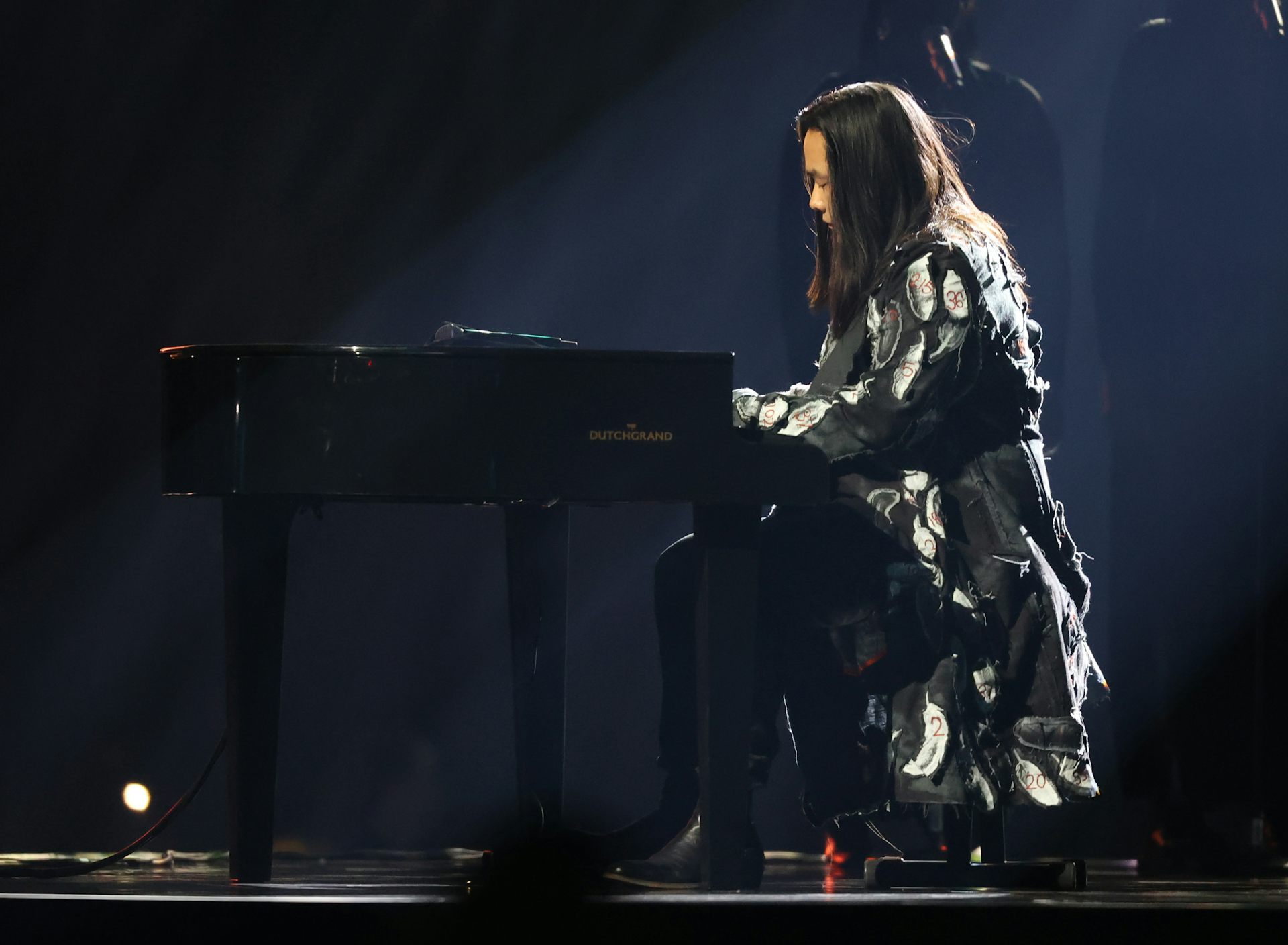A singer seen seated at a piano.