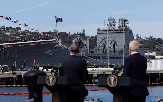US and Australian leaders look at a military ship.
