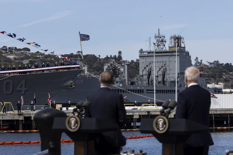 US and Australian leaders look at a military ship.