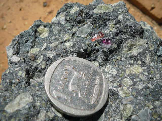 Kimberlite volcanic rock with fragments of crystal, with a penny for size reference.