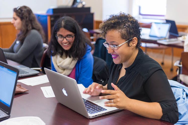 Women work together at a table with laptops