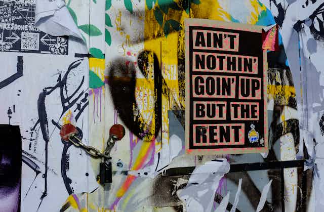 A poster on a padlocked door that reads: Ain't nothing going up but the rent