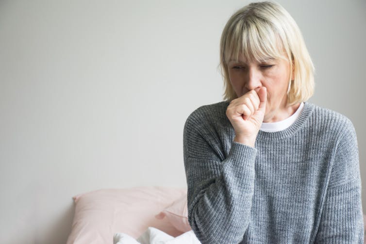 Woman in lounge room coughing into fist