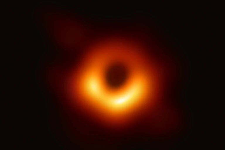 An orange donut shape with a brighter region towards the bottom, on a black background