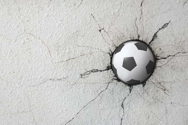 balón de fútbol inserto en una pared agrietada