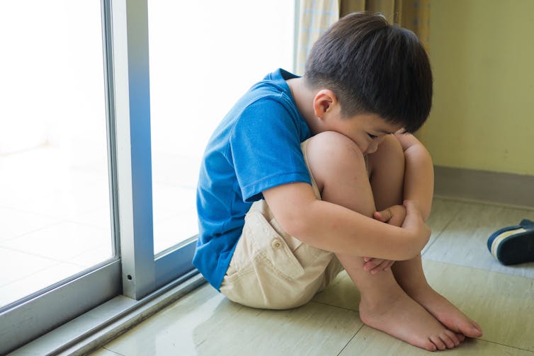 Sad child sat in front of glass door