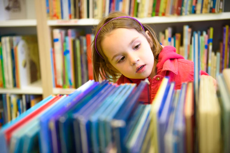 Petite fille choisissant un livre en bibliothèque