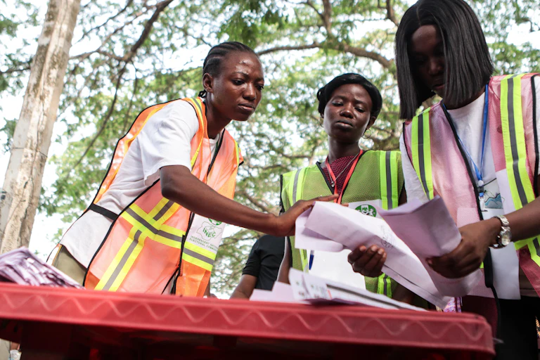Three women in high-visibility vests standing over a table looking through pieces of paper